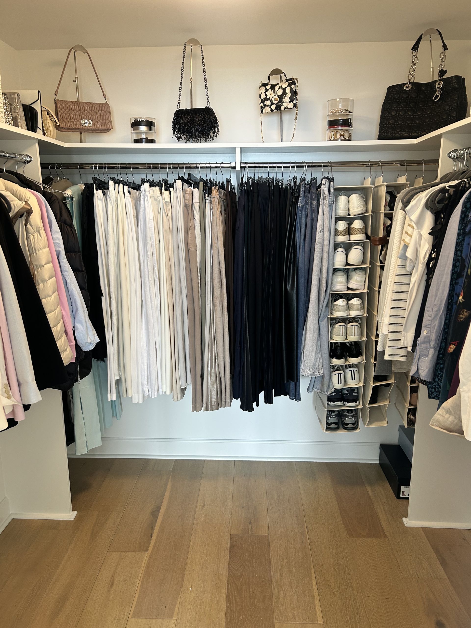 Walk-in closet with color-sorted clothing and handbag shelf